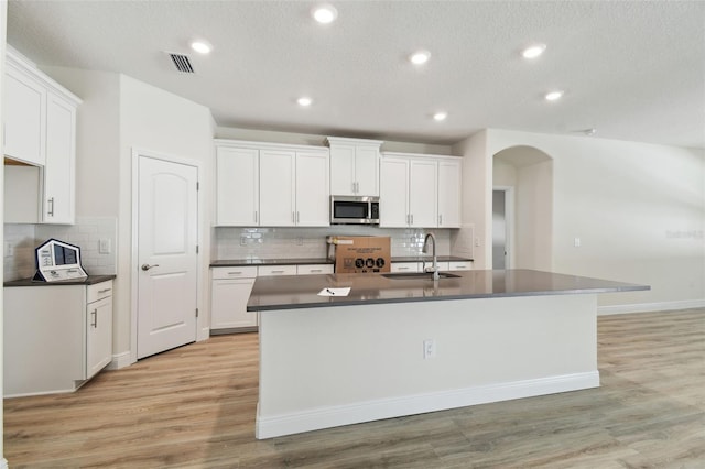 kitchen with sink, a center island with sink, and white cabinets