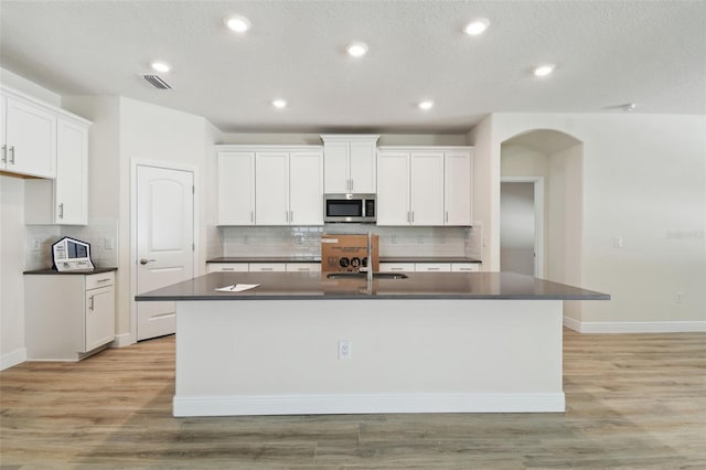 kitchen featuring white cabinetry, sink, and an island with sink