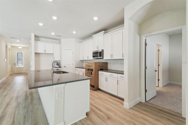 kitchen featuring white cabinetry, sink, an island with sink, and range