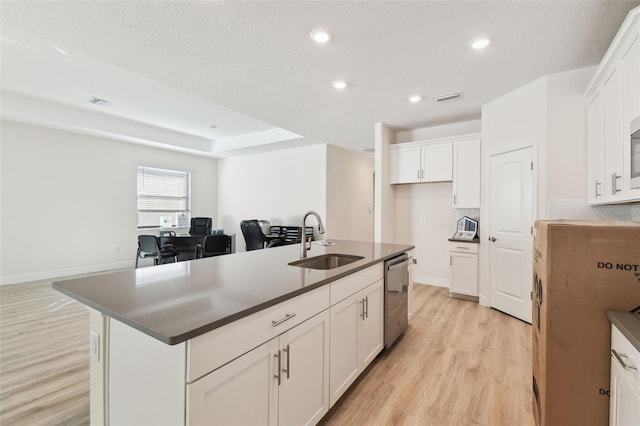 kitchen with sink, a kitchen island with sink, white cabinetry, stainless steel dishwasher, and light wood-type flooring