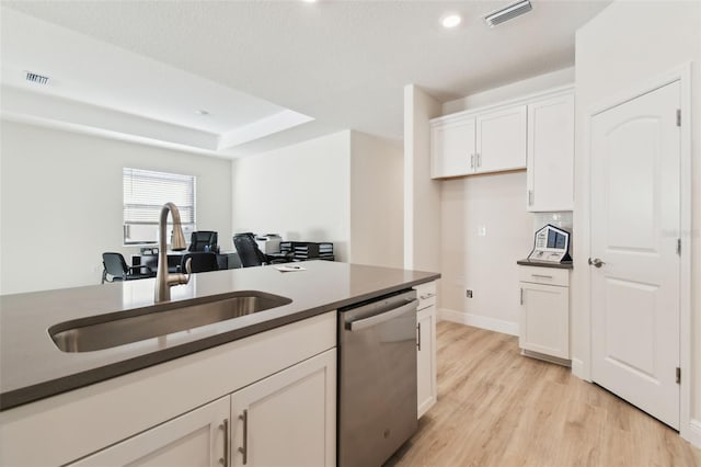 kitchen featuring sink, stainless steel dishwasher, a raised ceiling, light hardwood / wood-style floors, and white cabinets