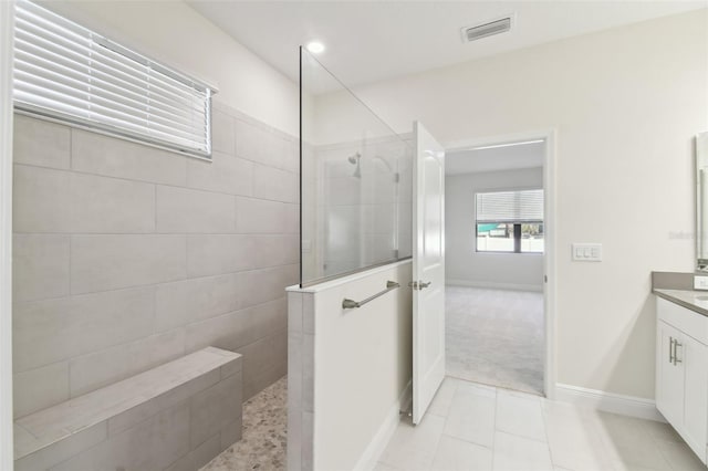 bathroom with vanity, tiled shower, and tile patterned floors