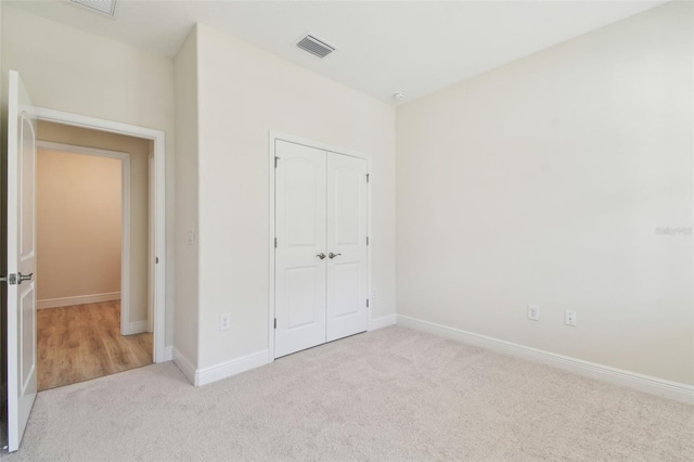 unfurnished bedroom featuring light carpet and a closet