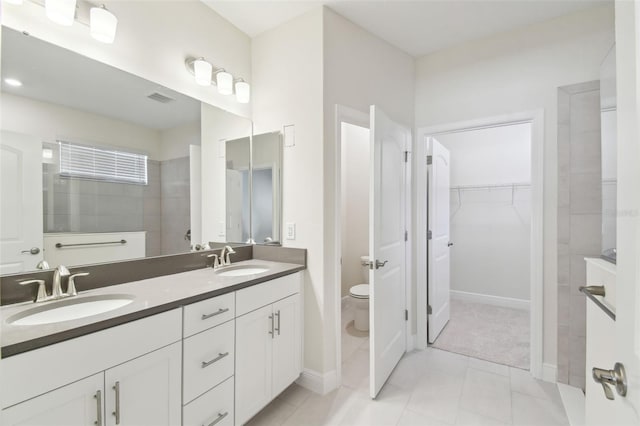 bathroom featuring tile patterned flooring, vanity, tiled shower, and toilet