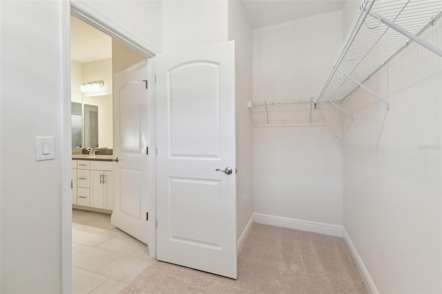 walk in closet with sink and light colored carpet