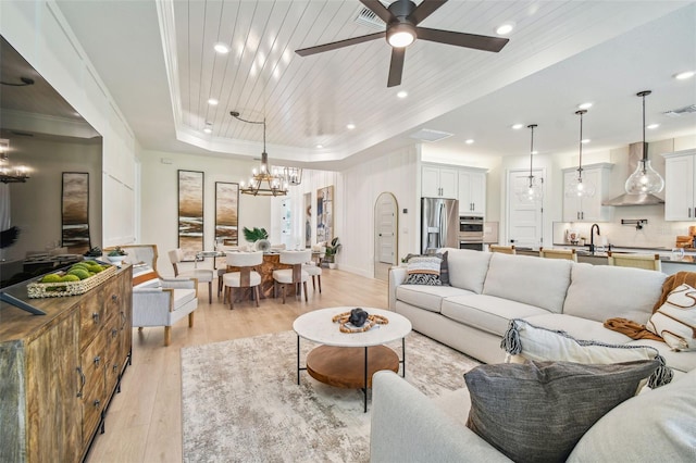 living room with ceiling fan with notable chandelier, a tray ceiling, wooden ceiling, and light hardwood / wood-style floors