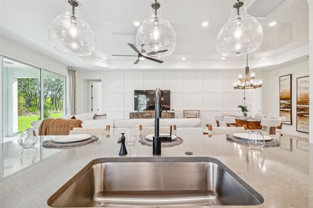 kitchen with pendant lighting, ornamental molding, a tray ceiling, and sink