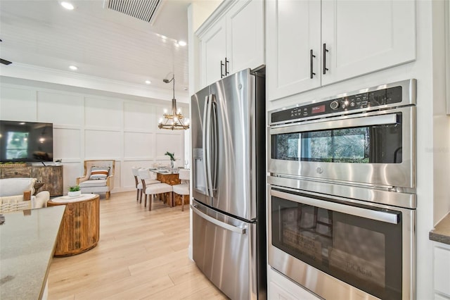 kitchen featuring pendant lighting, light hardwood / wood-style flooring, dark stone countertops, stainless steel appliances, and white cabinetry