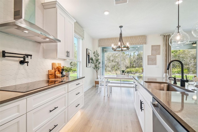 kitchen featuring wall chimney exhaust hood, light wood-type flooring, white cabinetry, dishwasher, and black electric stovetop