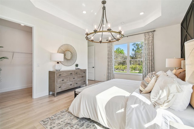 bedroom with ornamental molding, a raised ceiling, a chandelier, and light hardwood / wood-style floors