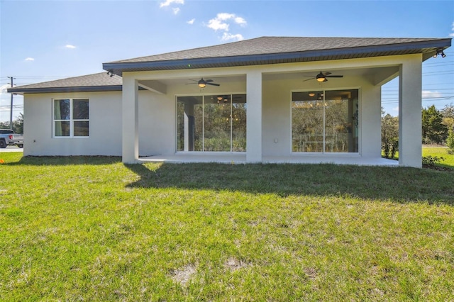 rear view of property with ceiling fan and a lawn