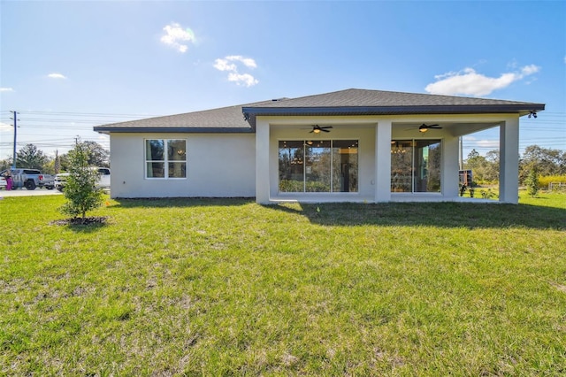 rear view of property with ceiling fan and a yard