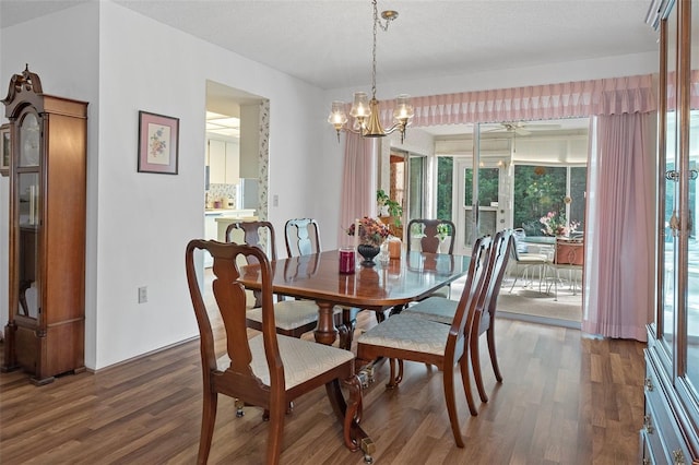 dining area with a textured ceiling, ceiling fan with notable chandelier, and dark hardwood / wood-style flooring