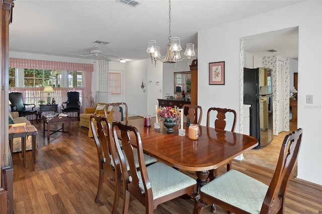 dining area featuring a textured ceiling, ceiling fan with notable chandelier, and hardwood / wood-style floors