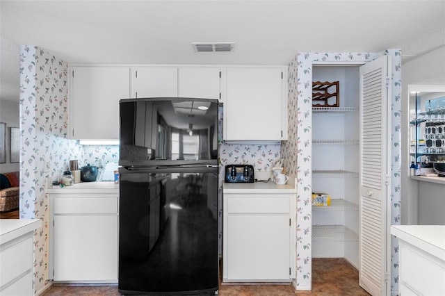 kitchen featuring white cabinets and black fridge