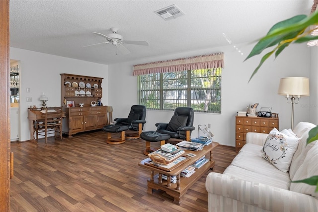 living room featuring a textured ceiling, dark wood-type flooring, and ceiling fan