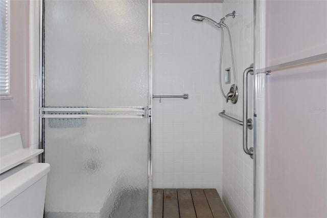 bathroom featuring toilet and a shower with shower door