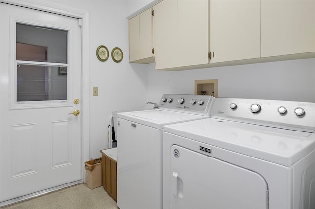 laundry room with washer and clothes dryer, light colored carpet, and cabinets