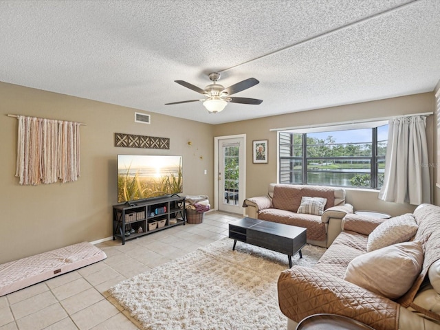 living room featuring a textured ceiling, ceiling fan, and light tile patterned flooring