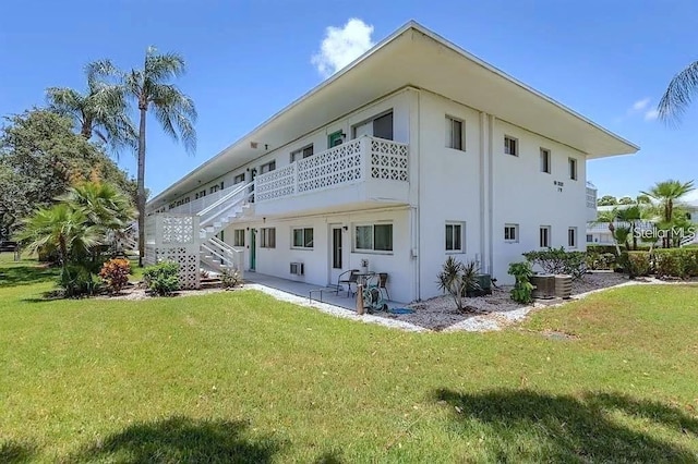 rear view of property featuring central AC unit, a yard, and a patio area