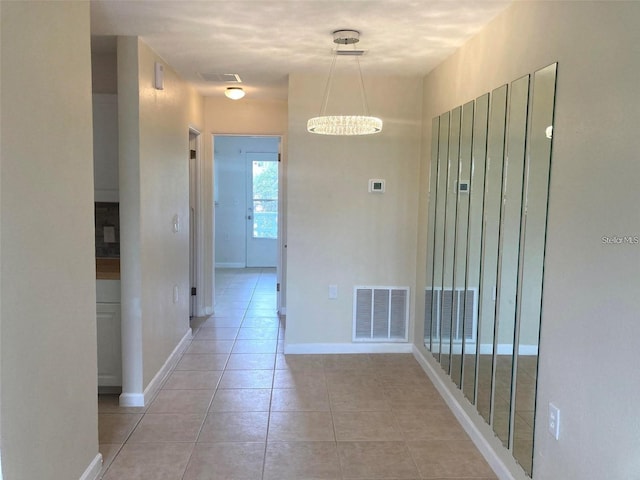 hallway with a notable chandelier and light tile patterned floors