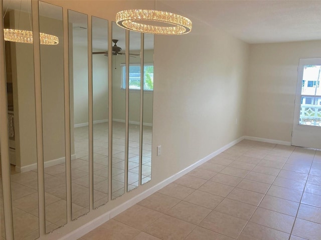 spare room featuring ceiling fan with notable chandelier and light tile patterned floors