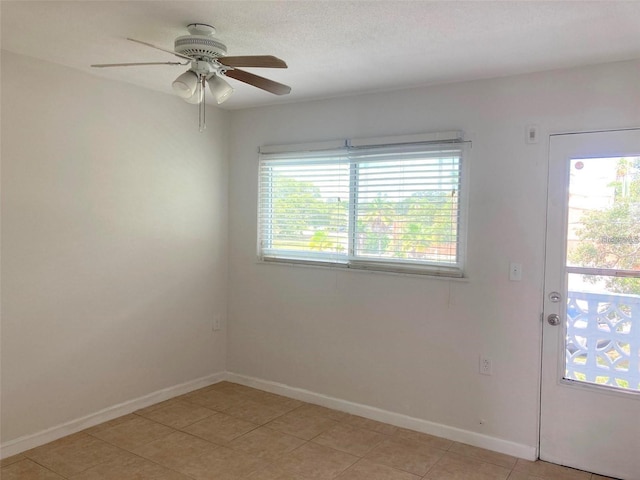 empty room featuring a textured ceiling, light tile patterned floors, and ceiling fan