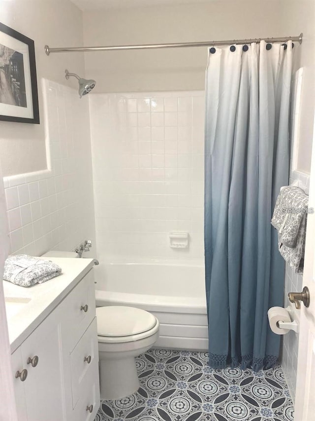 full bathroom with shower / tub combo with curtain, tile walls, vanity, and toilet