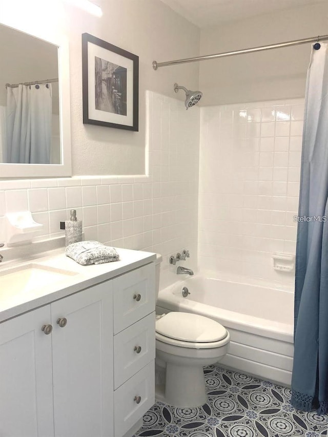 full bathroom featuring shower / bath combination with curtain, vanity, tile patterned floors, tile walls, and toilet