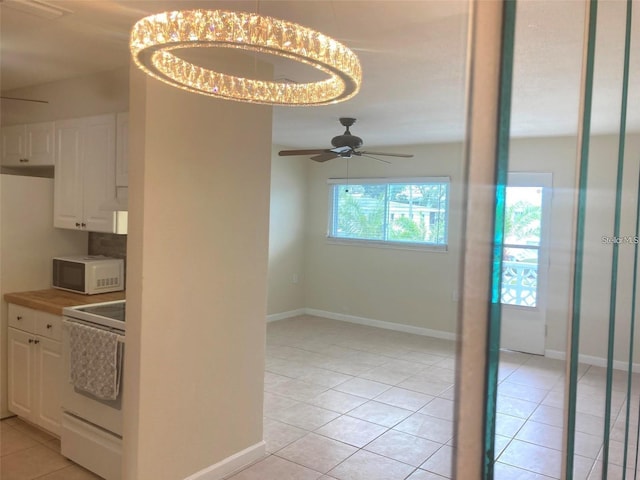 kitchen featuring white appliances, ceiling fan with notable chandelier, light tile patterned floors, and white cabinetry