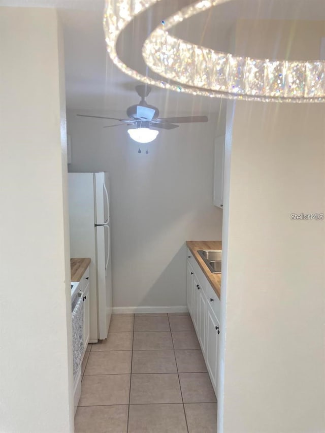 kitchen featuring ceiling fan, white cabinets, butcher block counters, white fridge, and light tile patterned floors