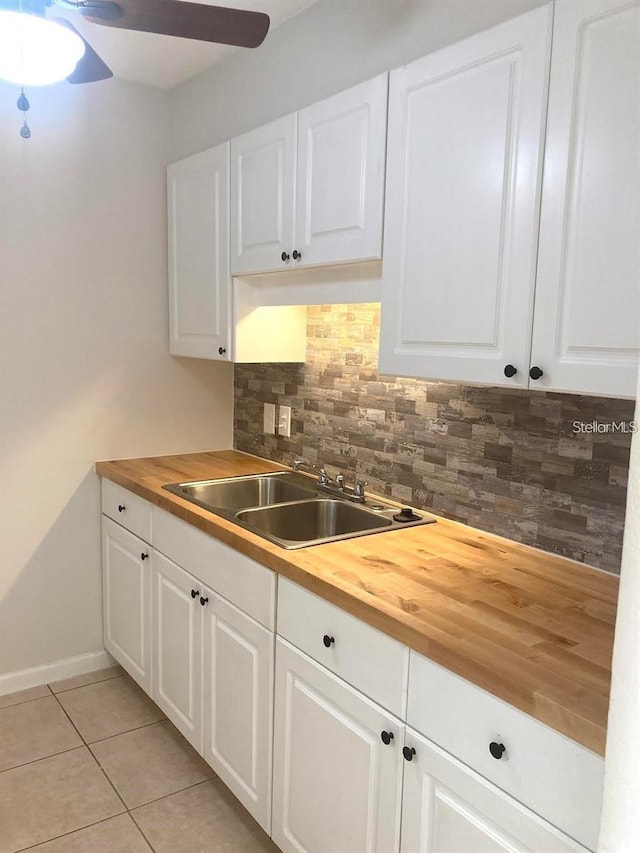 kitchen with wood counters, decorative backsplash, white cabinetry, and sink