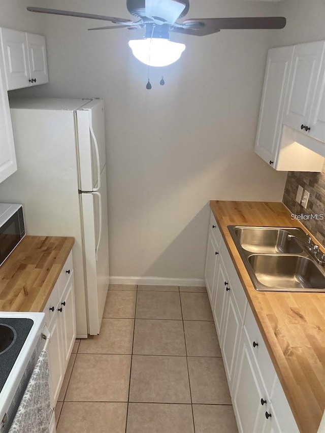 kitchen with ceiling fan, range, white cabinets, butcher block countertops, and light tile patterned floors