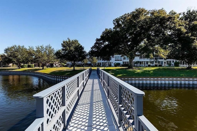 view of dock featuring a water view and a yard