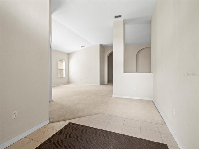 4264 Braemere Dr, Spring Hill, FL 34609 - empty room featuring light colored carpet, arched walkways, light tile patterned flooring, baseboards, and lofted ceiling