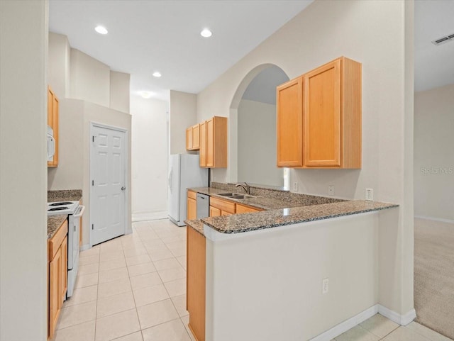4264 Braemere Dr, Spring Hill, FL 34609 - kitchen with white appliances, a sink, light tile patterned floors, a peninsula, and dark stone countertops