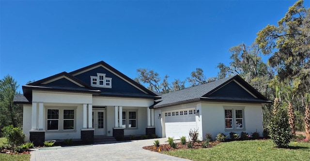 view of front of property featuring a front lawn, driveway, covered porch, an attached garage, and stucco siding