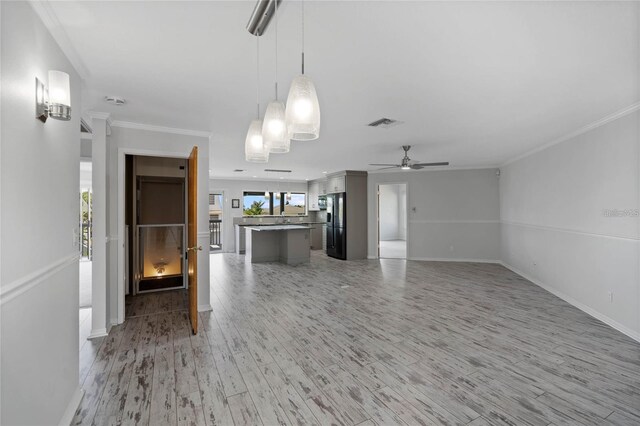 unfurnished living room with crown molding, a ceiling fan, light wood finished floors, and visible vents