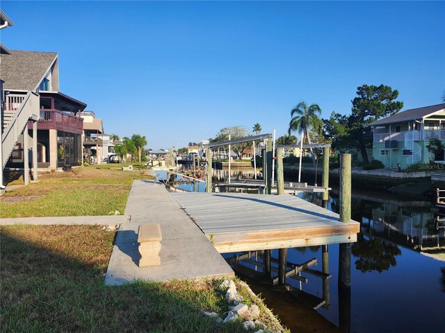 view of dock with a lawn, boat lift, a residential view, and a water view