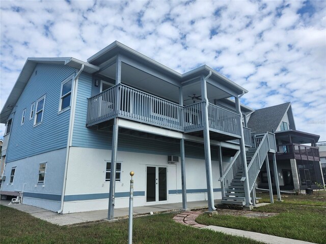 back of property with a ceiling fan, a balcony, and a wall mounted air conditioner