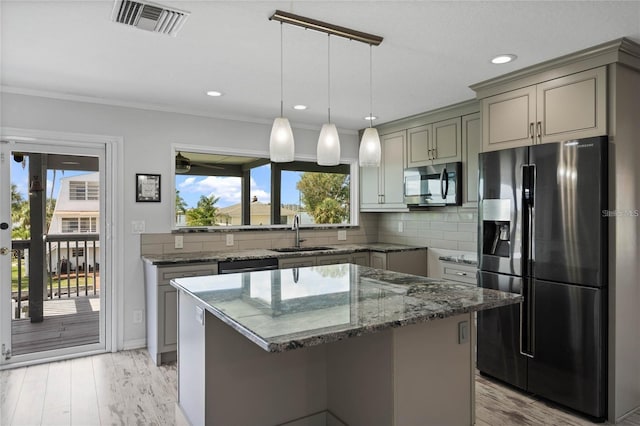 kitchen featuring dark stone countertops, light hardwood / wood-style flooring, appliances with stainless steel finishes, and a wealth of natural light