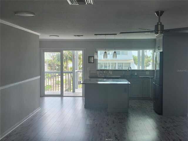 kitchen with a sink, freestanding refrigerator, a ceiling fan, visible vents, and ornamental molding