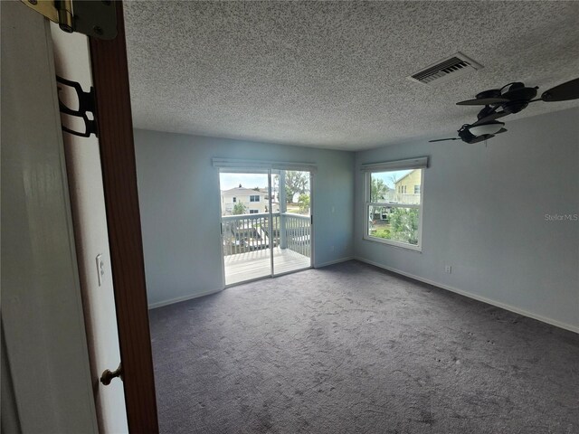 empty room with visible vents, carpet floors, baseboards, ceiling fan, and a textured ceiling