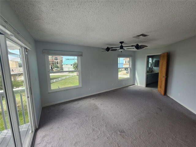 carpeted spare room featuring a ceiling fan, a textured ceiling, visible vents, and baseboards
