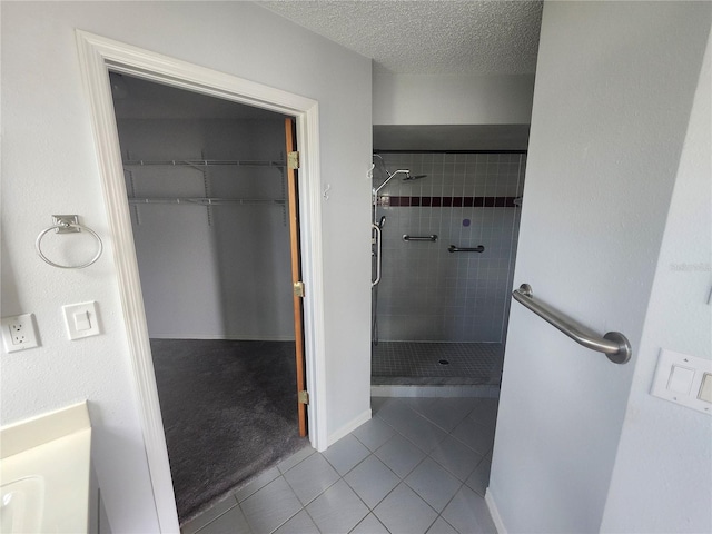 bathroom featuring a textured ceiling, tile patterned flooring, and tiled shower