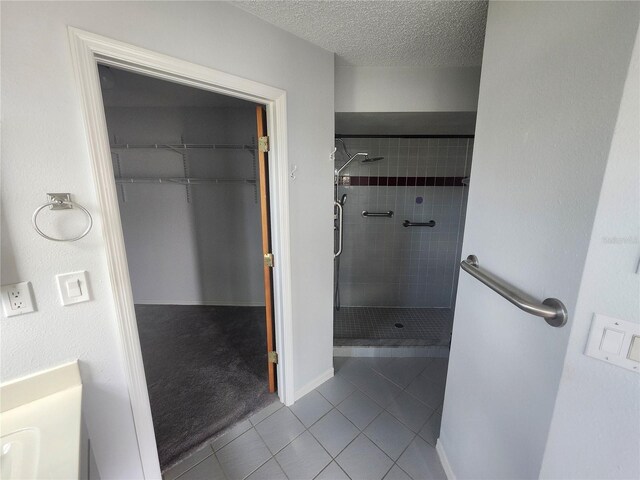 bathroom with a textured ceiling, tile patterned flooring, and a stall shower