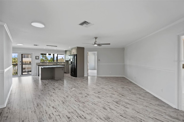 unfurnished living room featuring visible vents, crown molding, light wood-style floors, baseboards, and ceiling fan