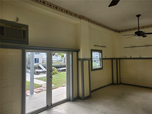 interior space with a ceiling fan, concrete floors, a textured ceiling, and a wall mounted AC