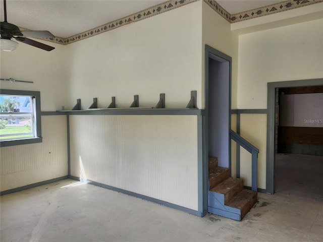 interior space with a ceiling fan, stairway, and unfinished concrete flooring