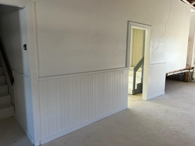 6428 Driftwood Dr, Hudson, FL 34667 - corridor featuring a wainscoted wall, stairway, and concrete floors